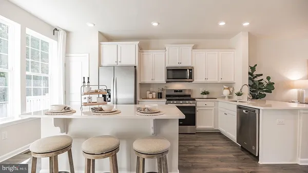 a kitchen with stainless steel appliances a dining table chairs microwave and stove