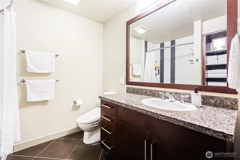 a bathroom with a granite countertop sink a toilet and a mirror