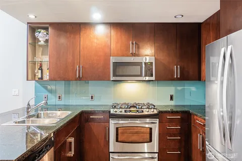 a kitchen with stainless steel appliances granite countertop a stove a sink and a microwave