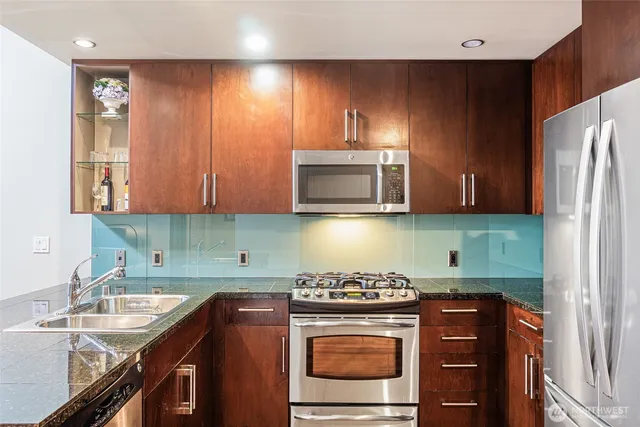 a kitchen with stainless steel appliances granite countertop a stove a sink and a microwave