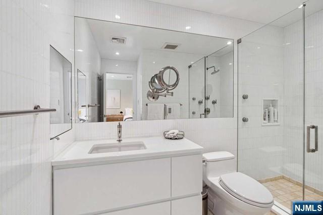 532 Winthrop Road Teaneck, NJ 07666 - Photo 21 of 42 a bathroom with a sink a toilet a mirror a vanity and shower