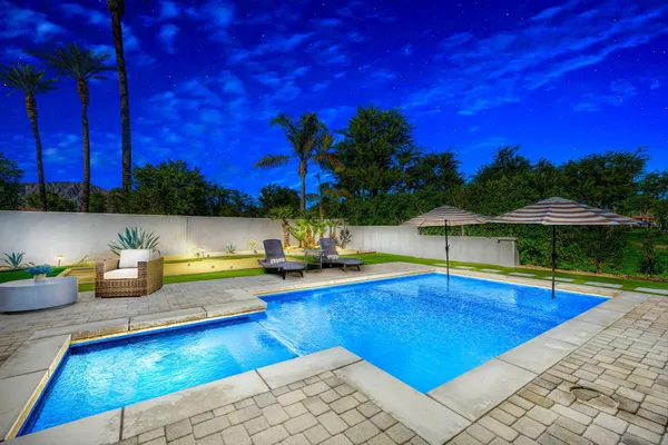 a view of swimming pool with seating area and trees in the background