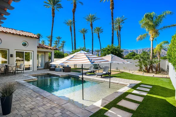 a view of a house with backyard sitting area and swimming pool