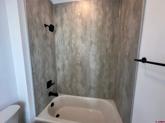 a bathroom with a bathtub shower sink vanity and toilet