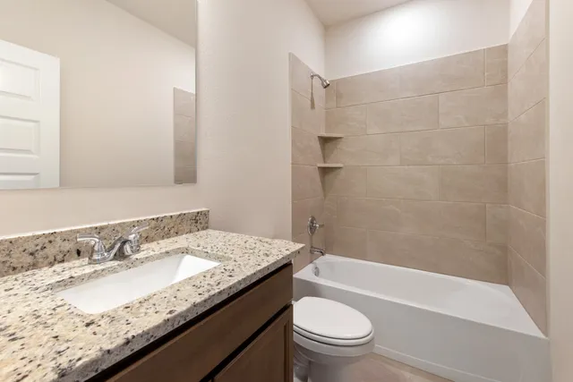 a bathroom with a granite countertop sink a toilet and bathtub