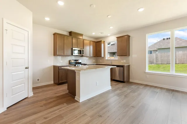 a kitchen with a refrigerator a stove top oven a sink and a window