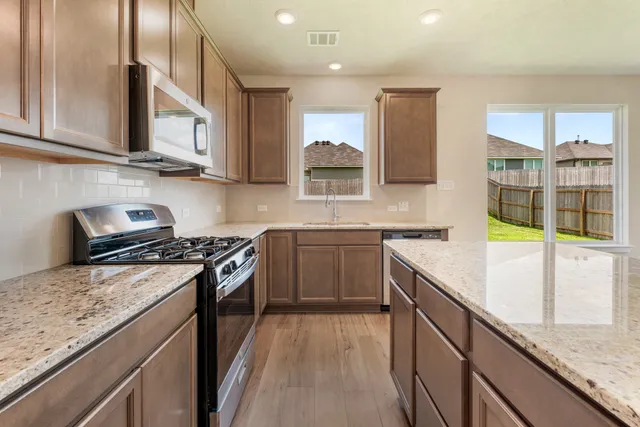 a kitchen with stainless steel appliances granite countertop a stove a sink and a microwave