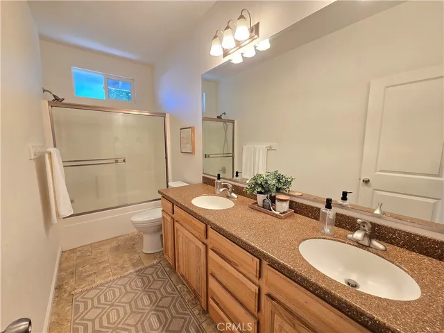 a bathroom with a granite countertop sink a toilet a mirror a vanity and shower