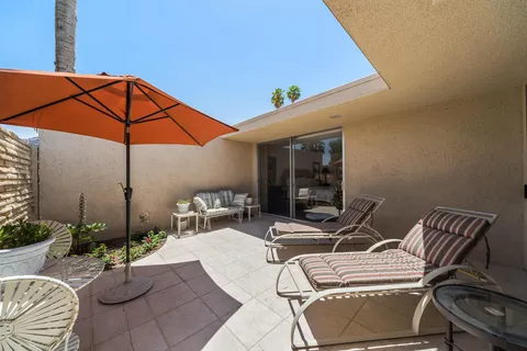 a patio with table and chairs and potted plants
