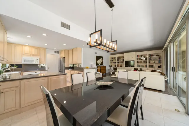 a large kitchen with a dining table chairs sink and cabinets