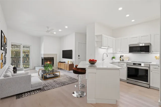 a kitchen with stainless steel appliances kitchen island granite countertop a sink and a stove top oven with wooden floor