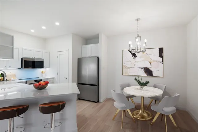 a kitchen with stainless steel appliances a dining table chairs and a refrigerator