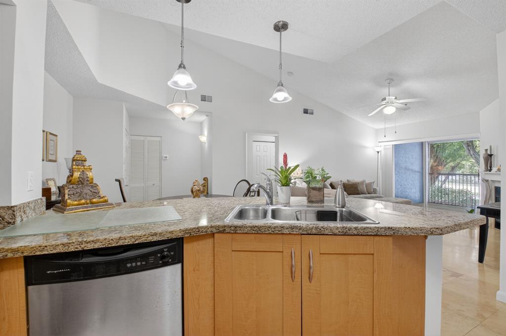 3237 Clint Moore Road, Unit 206 Boca Raton, FL 33496 - Photo 13 of 49 a kitchen with kitchen island granite countertop a sink cabinets and wooden floor