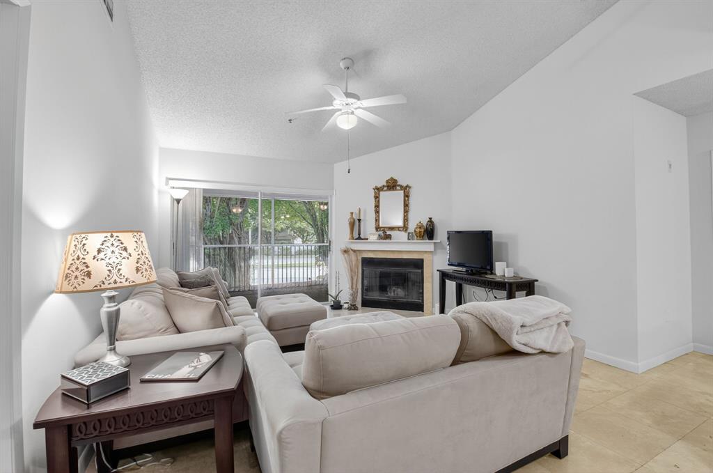 3237 Clint Moore Road, Unit 206 Boca Raton, FL 33496 - Photo 6 of 49 a living room with furniture a fireplace and a chandelier