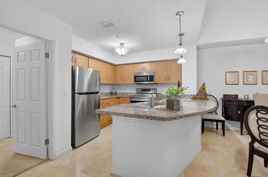 3237 Clint Moore Road, Unit 206 Boca Raton, FL 33496 - Photo 10 of 49 a kitchen with stainless steel appliances granite countertop a refrigerator a stove a sink a dining table and chairs with wooden floor