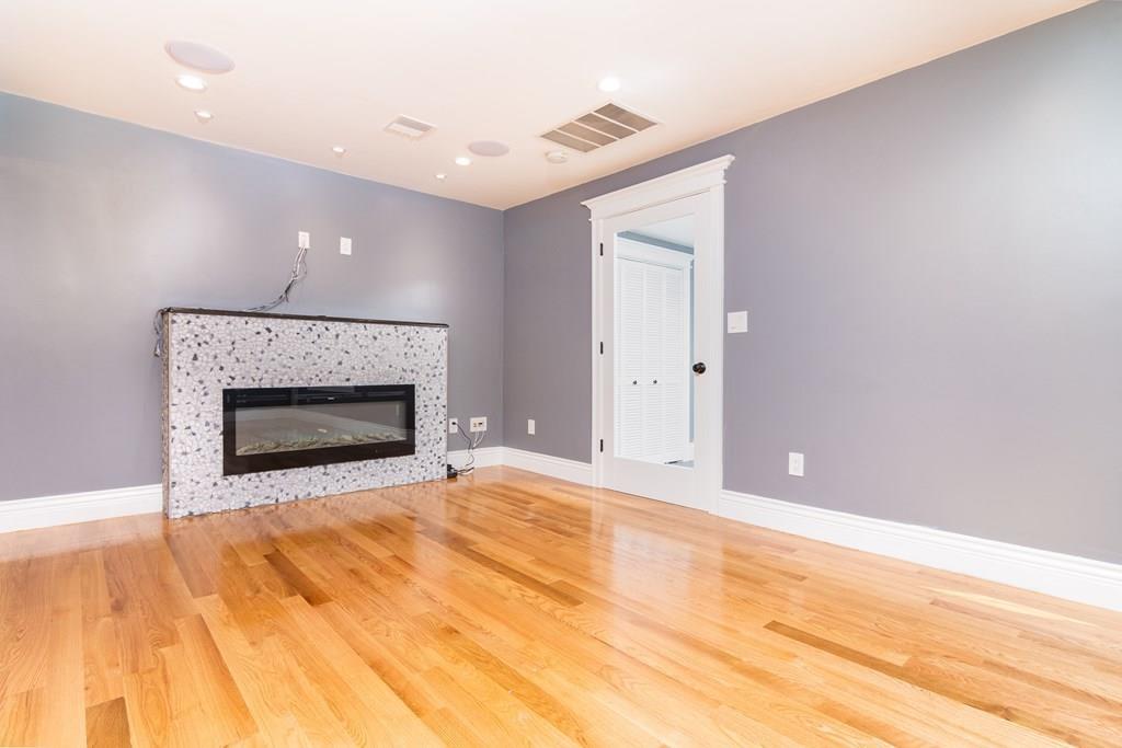 23 Amelian Road Randolph, MA 02368 - Photo 11 of 39 a view of empty room with wooden floor and fireplace