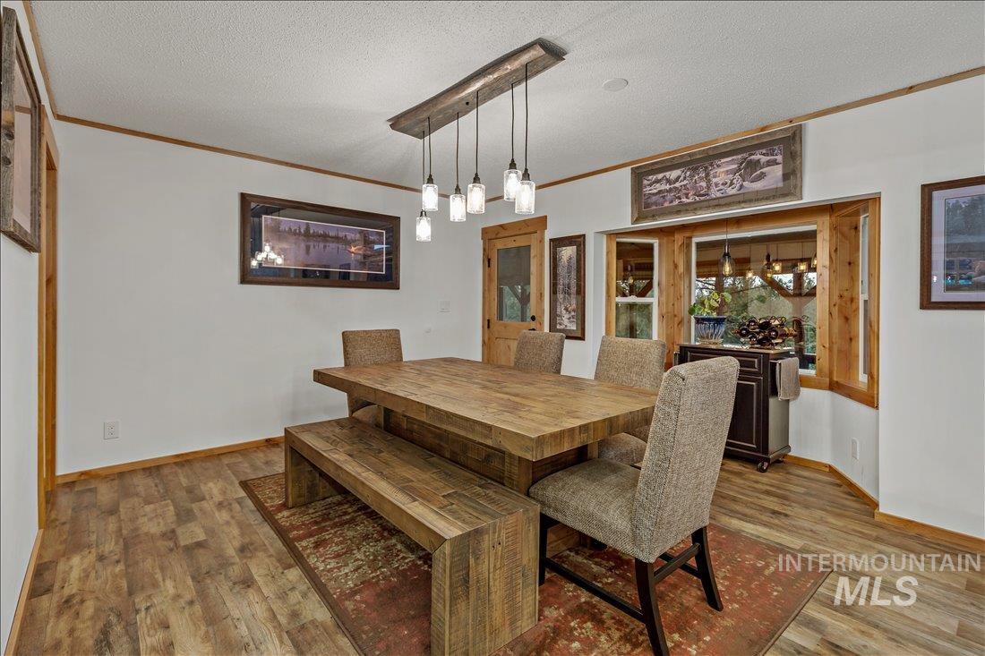 79 Sunset Loop Cascade, ID 83611 - Photo 13 of 44 Dining area featuring wood-finish flooring, white walls with wood trim, and a prominent bay window