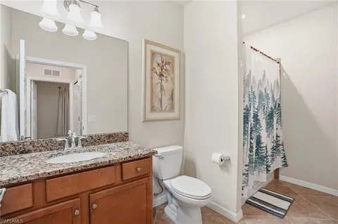 a bathroom with a granite countertop toilet a sink and a mirror