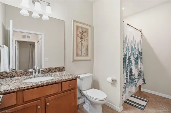 a bathroom with a granite countertop toilet a sink and a mirror