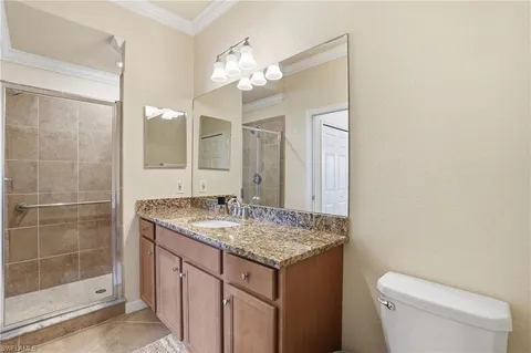 a bathroom with a granite countertop sink a toilet a mirror and shower
