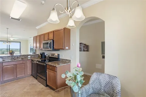 a kitchen with stainless steel appliances granite countertop a sink a stove a dining table and chairs with wooden floor