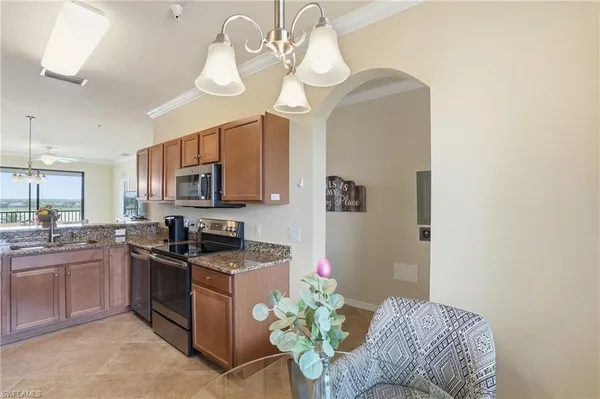 a kitchen with stainless steel appliances granite countertop a sink a stove a dining table and chairs with wooden floor