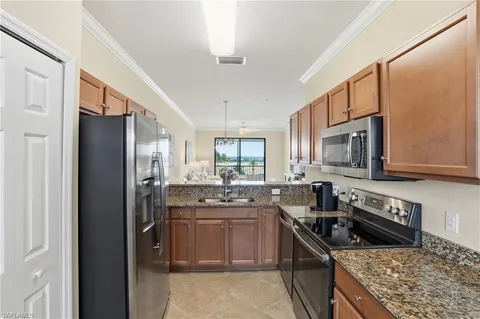 a kitchen with stainless steel appliances granite countertop a stove top oven a sink dishwasher a refrigerator and cabinets with wooden floor