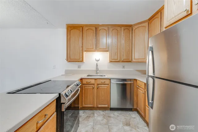 a kitchen with stainless steel appliances granite countertop a refrigerator sink and stove
