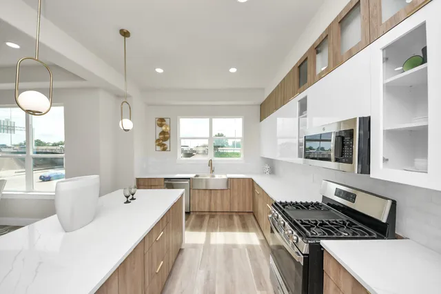 a large kitchen with kitchen island a large counter space a large window and stainless steel appliances