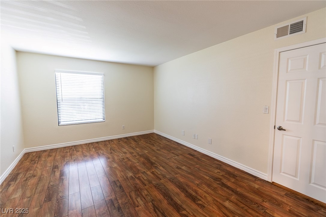 2451 North Rainbow Boulevard, Unit 1116 Las Vegas, NV 89108 - Photo 18 of 28 Empty room featuring dark wood finished floors and baseboards