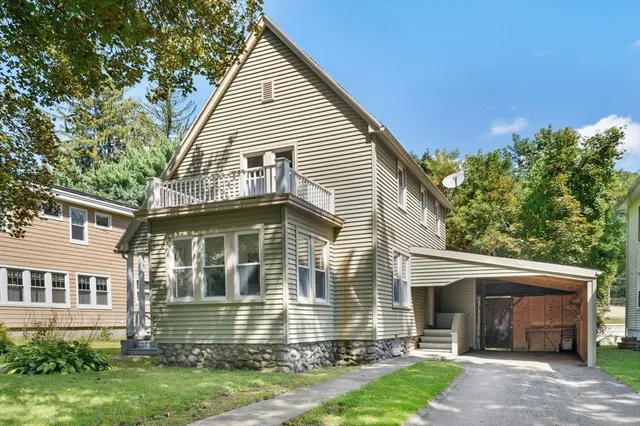 a view of a house that has a small yard and large trees
