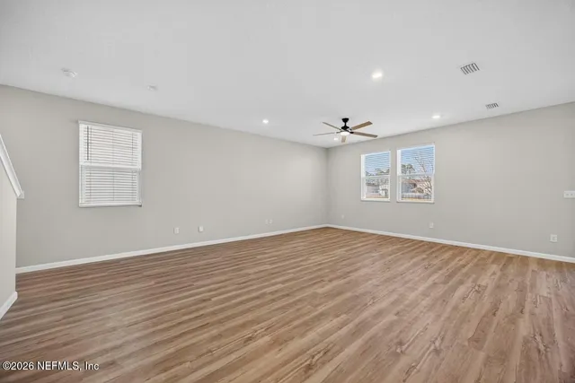 a large kitchen with stainless steel appliances granite countertop a stove a sink dishwasher a refrigerator and white cabinets with wooden floor