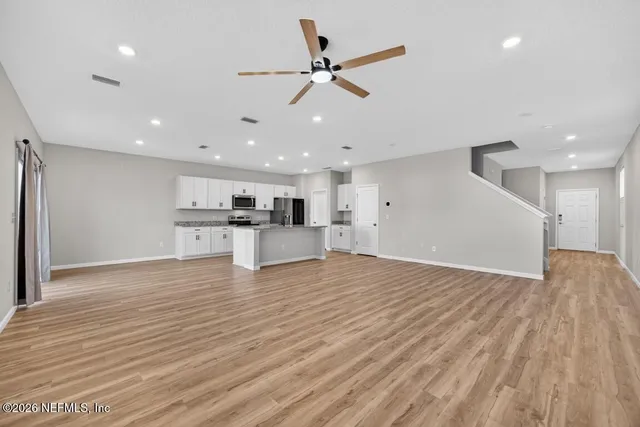 a kitchen that has a lot of white cabinets and stainless steel appliances