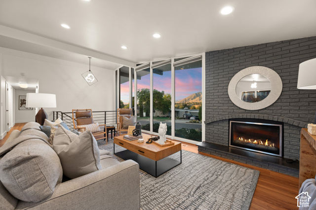 8678 Mount Majestic Road Sandy, UT 84093 - Photo 7 of 37 Recessed lighting, wood-finish flooring, full-height windows, a gray brick fireplace with an integrated firebox, and a metal railing