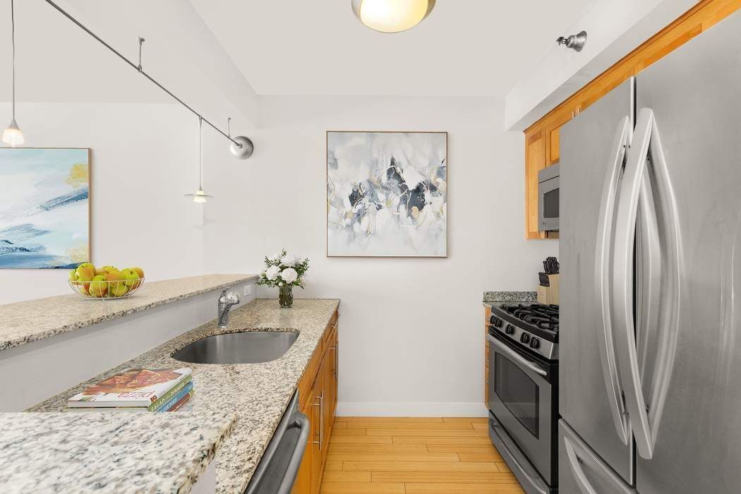516 West 47th Street, Unit N6A Manhattan, NY 10036 - Photo 3 of 16 a kitchen with stainless steel appliances granite countertop a refrigerator a sink and a stove