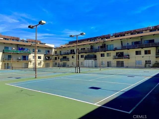 a view of a tennis ground with large trees