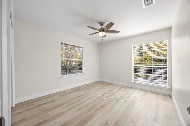 a view of an empty room with a window and wooden floor