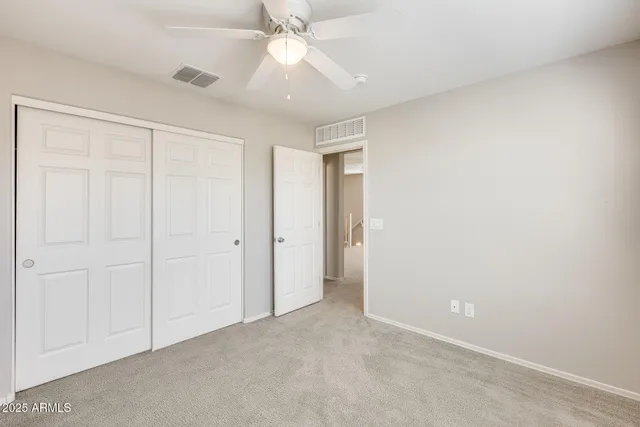an empty room with a chandelier fan and closet area