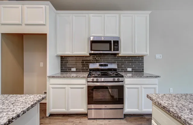 a kitchen with granite countertop a stove sink and cabinets