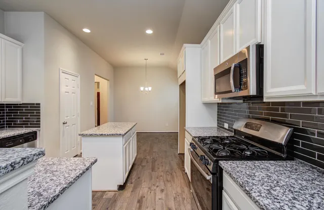 a kitchen with stainless steel appliances granite countertop a stove a sink and a microwave