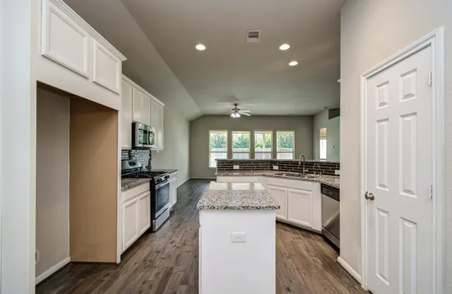 a kitchen with stainless steel appliances granite countertop a refrigerator a stove and a sink