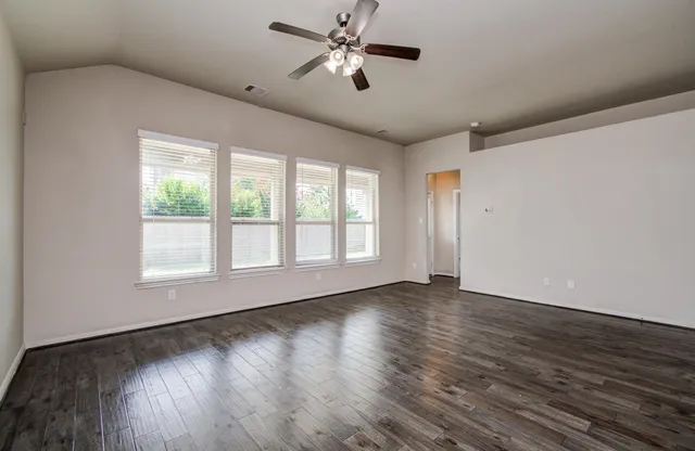 a view of empty room with wooden floor and fan