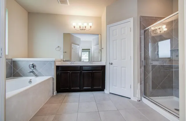 a spacious bathroom with a tub sink and mirror