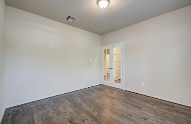 an empty room with wooden floor and windows