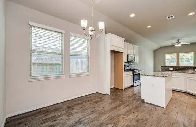 a view of a kitchen with granite countertop wooden floor stainless steel appliances and a window