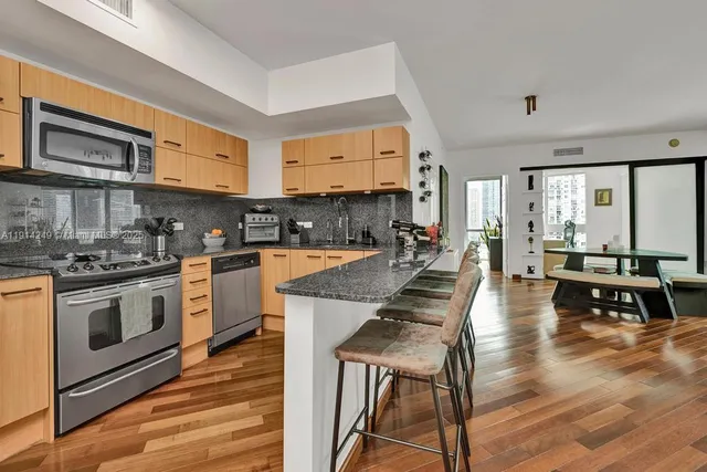 a kitchen with stainless steel appliances granite countertop a stove top oven a sink dishwasher and white cabinets with wooden floor