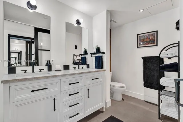 a bathroom with a double vanity sink a toilet and a mirror