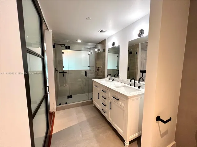 a bathroom with a double vanity sink mirror and shower
