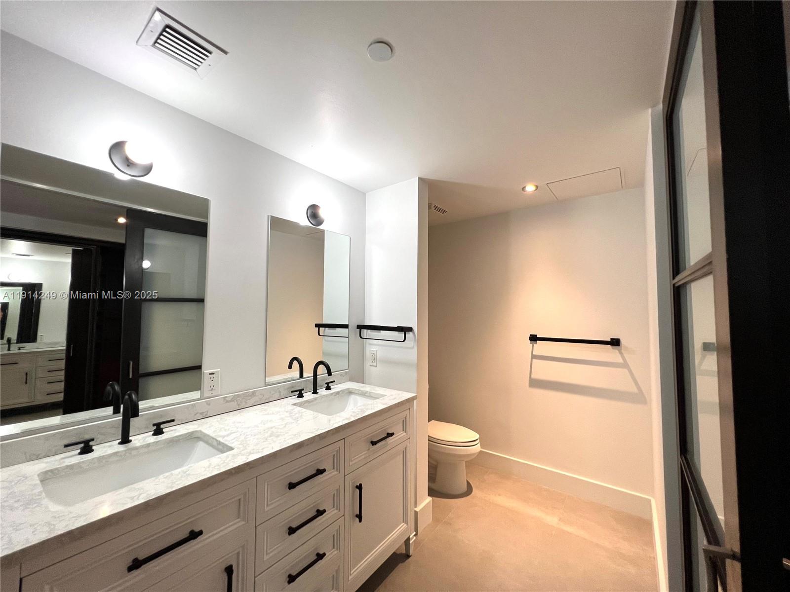 350 South Miami Avenue, Unit 1502 Miami, FL 33130 - Photo 17 of 30 a bathroom with a double vanity sink a mirror and a toilet