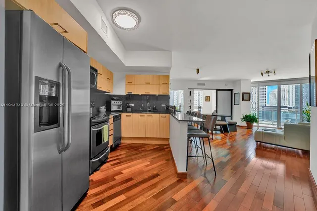 a kitchen with stainless steel appliances granite countertop a refrigerator a stove and a wooden floors